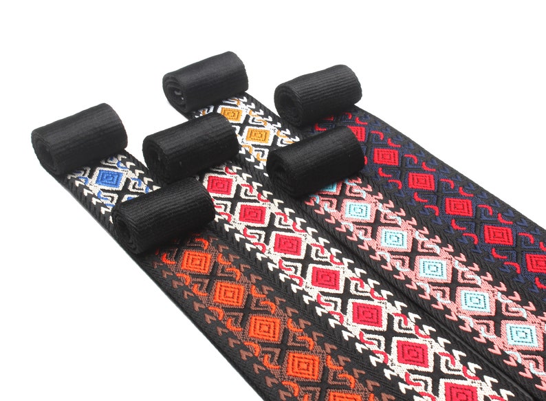 Peut inclure: Cinq galons tiss&eacute;s noirs avec des motifs g&eacute;om&eacute;triques color&eacute;s. Les motifs comprennent du rouge, du bleu, de l'orange, du rose et du blanc.