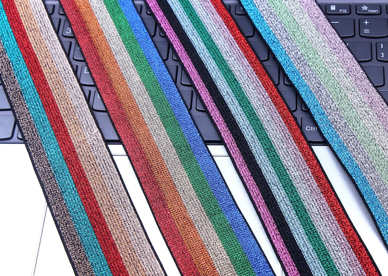 Pu&ograve; includere: Assortimento di passamanerie elastiche colorate con un effetto metallizzato. La passamaneria presenta pi&ugrave; strisce di colori diversi, tra cui rosso, arancione, verde, blu e viola.