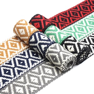 May include: A set of six woven trim ribbons in various colors, including gold, black, white, green, and red. The ribbons feature a geometric diamond pattern.