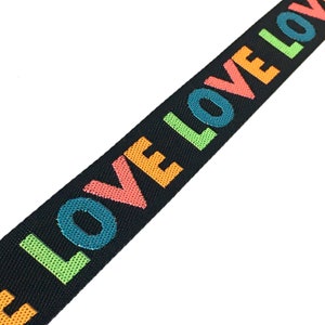 Puede incluir: Cinta elástica negra con la palabra "LOVE" repetida en colores arcoíris.