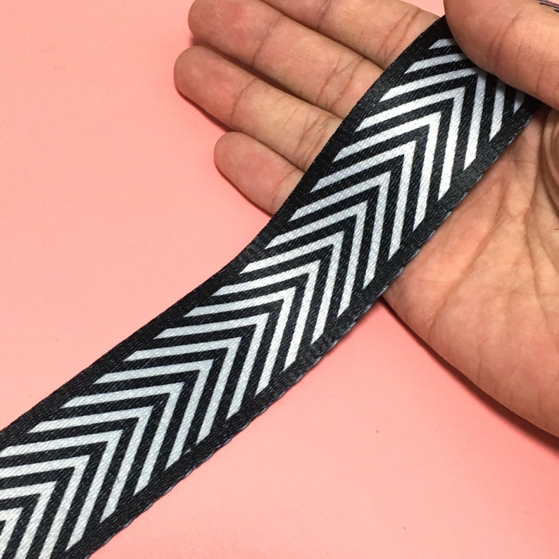 K&ouml;nnte beinhalten: Schwarz-wei&szlig;es Chevron-Band. Das Band ist mit einem silbernen Faden gewebt, was ihm einen dezenten Glanz verleiht.