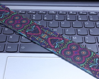 Peut inclure: Une sangle de guitare à motif coloré avec un motif paisley dans des tons de rose, bleu, vert et jaune.
