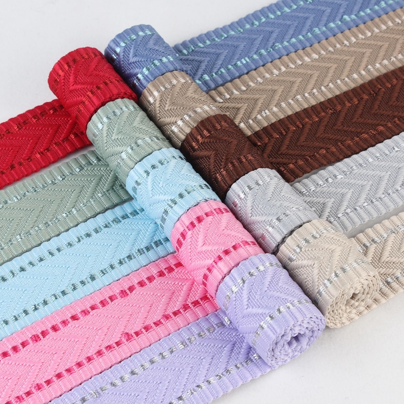 May include: Assortment of woven ribbon trim with a chevron pattern and silver accents. The ribbon trim comes in a variety of colors including light blue, pink, lavender, brown, beige, and gray.