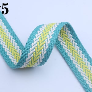May include: A turquoise, white, and yellow woven ribbon with a chevron pattern. #5