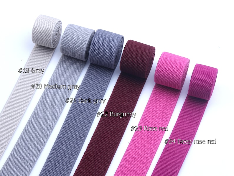 May include: Six different colors of elastic webbing, from left to right: gray, medium gray, dark gray, burgundy, rose red, and deep rose red.  The webbing is rolled up and laid out in a row.  #19 Gray, #20 Medium gray, #21 Dark gray, #22 Burgundy, #23 Rose red, #24 Deep rose red.