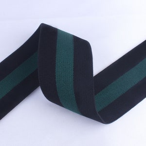 May include: Black elastic trim with two green stripes. The trim is folded and twisted.