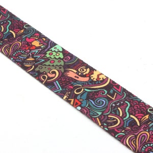 K&ouml;nnte beinhalten: Ein farbenfrohes gemustertes Stoffband mit dunklem Hintergrund und einer Vielzahl von Formen und Farben, darunter Gr&uuml;n, Blau, Rot, Gelb und Orange.