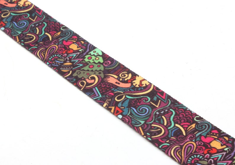 K&ouml;nnte beinhalten: Ein farbenfrohes gemustertes Stoffband mit dunklem Hintergrund und einer Vielzahl von Formen und Farben, darunter Gr&uuml;n, Blau, Rot, Gelb und Orange.