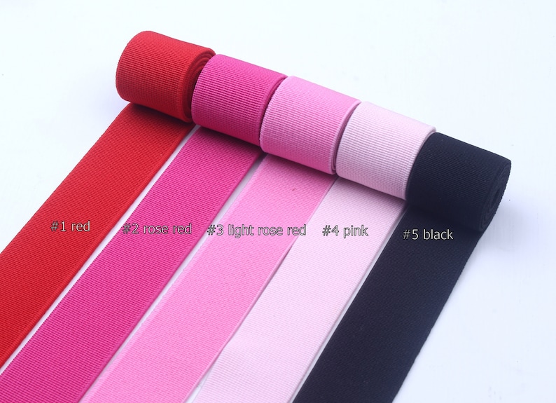 May include: Five rolls of elastic ribbon in different colors: red, rose red, light rose red, pink, and black. The ribbon is arranged in a row with the rolls stacked on top of each other.