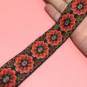 May include: Black trim with red and gold embroidered flowers. This trim is perfect for adding a touch of elegance to any project.