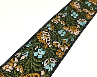 Peut inclure: Garniture à motifs floraux verts, bleus, roses et dorés sur fond noir.