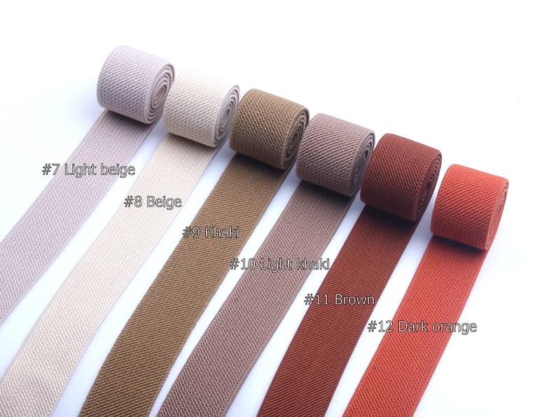May include: Six different colors of elastic webbing, from light beige to dark orange, with the color names and numbers written below each sample.