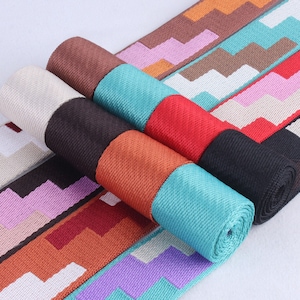 May include: Assortment of colorful woven trim with a zig-zag pattern. The trim is rolled up and arranged in a fan shape.