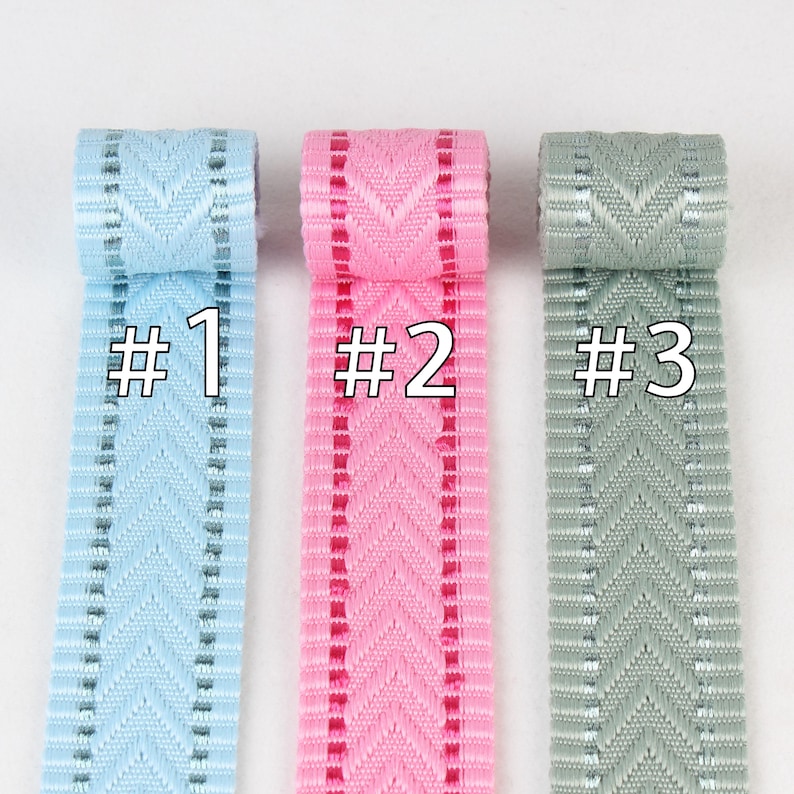 May include: Three rolls of ribbon with a chevron pattern. The ribbon is light blue, pink, and gray. The ribbon is labeled #1, #2, and #3.