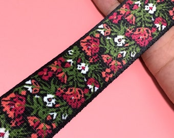 Peut inclure: Ruban tissé noir avec un motif floral dans les tons de rouge, vert et blanc.