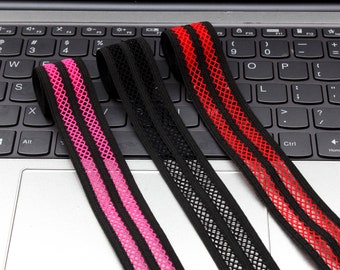 May include: Three elastic bands with a black mesh and two colored stripes. The bands are pink, black, and red.