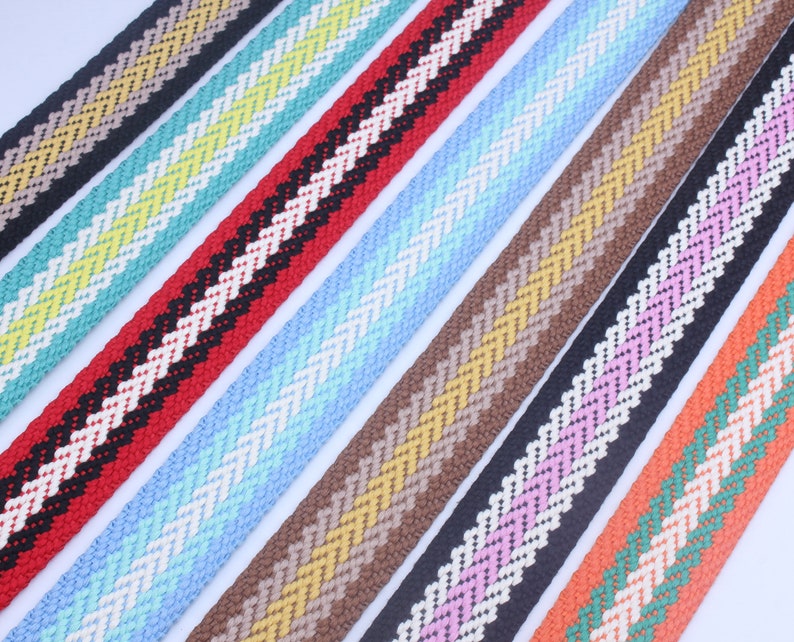 May include: Assortment of colorful striped woven ribbon with a chevron pattern. The ribbons are in various colors including red, blue, brown, pink, and orange.