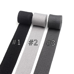 May include: Three rolls of woven cotton webbing in black, gray, and dark gray. The rolls are labeled #1, #2, and #3.