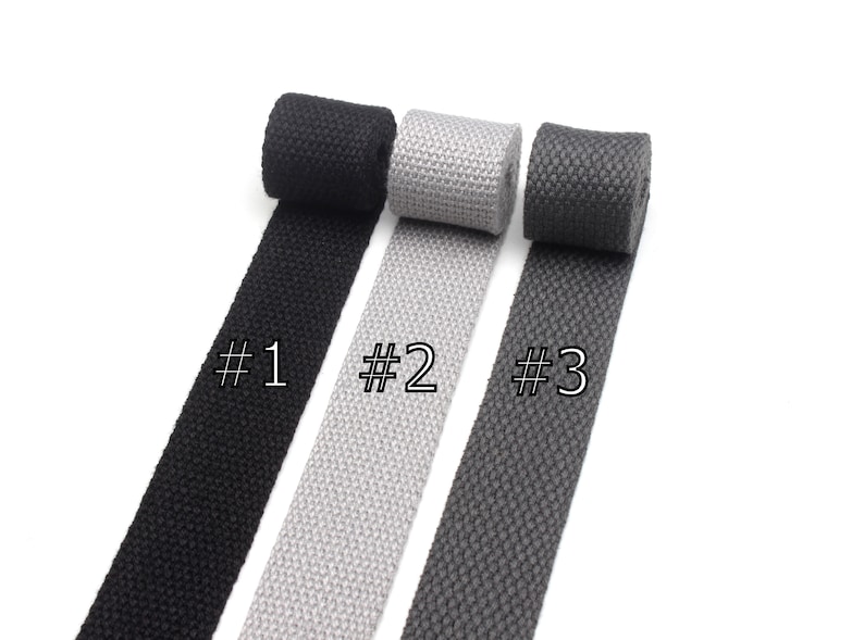 May include: Three rolls of woven cotton webbing in black, gray, and dark gray. The rolls are labeled #1, #2, and #3.