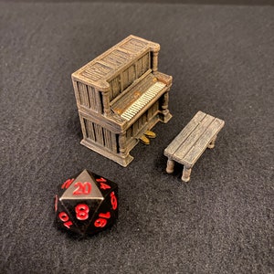 May include: Miniature brown piano with a matching bench and a black and red twenty-sided die. The piano has a detailed design, including keys and pedals. The die has red numbers and is used for tabletop games.
