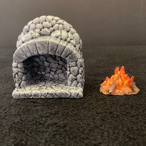 May include: A miniature stone fireplace with a small orange and brown fire in front of it. The fireplace is made of gray stone and has a rounded archway.