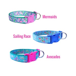 May include: Three dog collars with different patterns. The top collar is pink and green with a mermaid design. The middle collar is blue and white with a sailing race design. The bottom collar is teal and green with an avocado design. Each collar has a pink or blue buckle and a silver ring.
