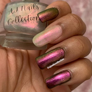 Puede incluir: Una mano de maniqu&iacute; con esmalte de u&ntilde;as iridiscente rosa claro, verde y morado. El esmalte de u&ntilde;as es de la colecci&oacute;n AJ Nails. El nombre de usuario de Instagram @ajnailscollection est&aacute; escrito en una de las u&ntilde;as.