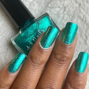 May include: A teal green nail polish with a shimmery finish. The polish is in a clear glass bottle with a black cap. The bottle is labelled "All Nails".