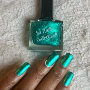 May include: A teal green nail polish bottle with a label that reads "AJ Nails Collection" and a heart symbol. A hand with teal green nail polish on each finger is shown.