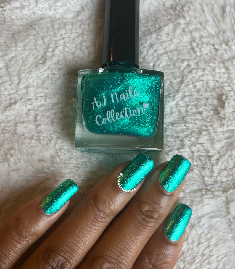 May include: A teal green nail polish bottle with a label that reads "AJ Nails Collection" and a heart symbol. A hand with teal green nail polish on each finger is shown.