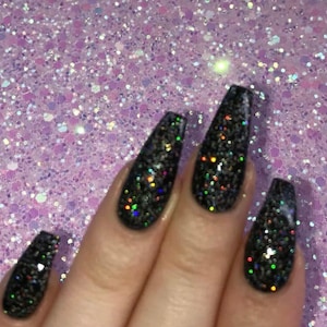 Peut inclure: Gros plan sur une main avec de longs ongles noirs recouverts de paillettes irisées.