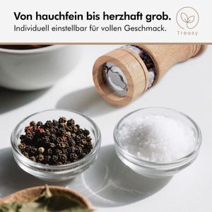 K&ouml;nnte beinhalten: Eine Pfefferm&uuml;hle aus Holz mit einem transparenten Glasteil, neben kleinen Glasschalen mit schwarzen Pfefferk&ouml;rnern und wei&szlig;em Salz. Der Text lautet: "Von hauchfein bis herzhaft grob. Individuell einstellbar f&uuml;r vollen Geschmack."