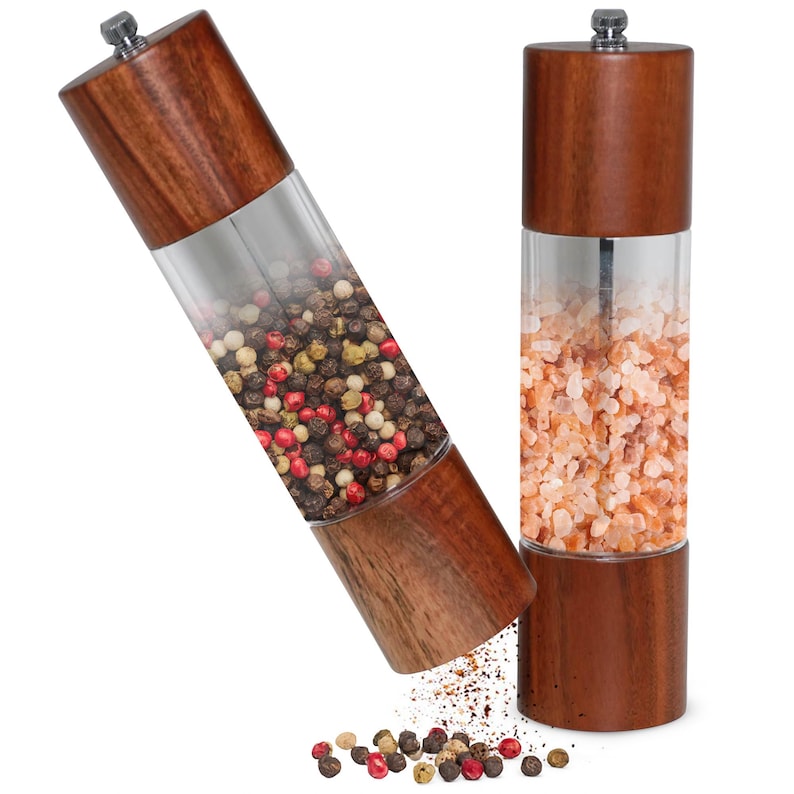 May include: Two wooden salt and pepper grinders with clear acrylic midsections. One grinder is filled with a mix of peppercorns, the other with pink Himalayan salt. The grinders are brown with a silver top.