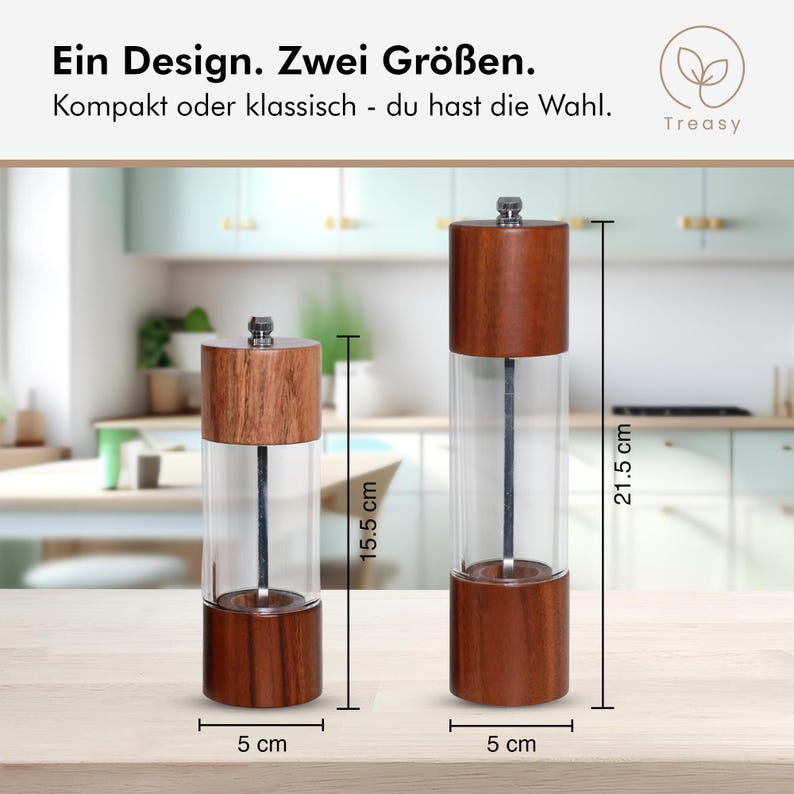 May include: Two wooden and glass pepper grinders, one 6.1 inches tall and the other 8.5 inches tall, each 2 inches wide. The grinders have a clear glass body and a wooden top and bottom. The text reads "Ein Design. Zwei Gr&ouml;&szlig;en. Kompakt oder klassisch - du hast die Wahl."