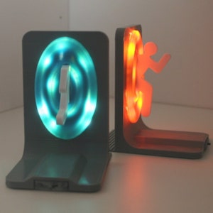 May include: A pair of bookends with a glowing blue and orange light. The bookends are shaped like a portal and a person stepping through the portal.