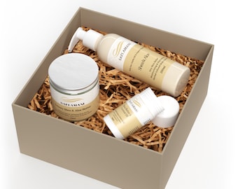 May include: A gift box filled with brown shredded paper contains three skincare products: a jar of Luxury Shea & Aloe Butter, a bottle of Shea & Aloe Moisturizing Body Lotion, and a tube of Hair Butter & Coconut Oil. All products are labeled with the brand name "SAFI AMANI".