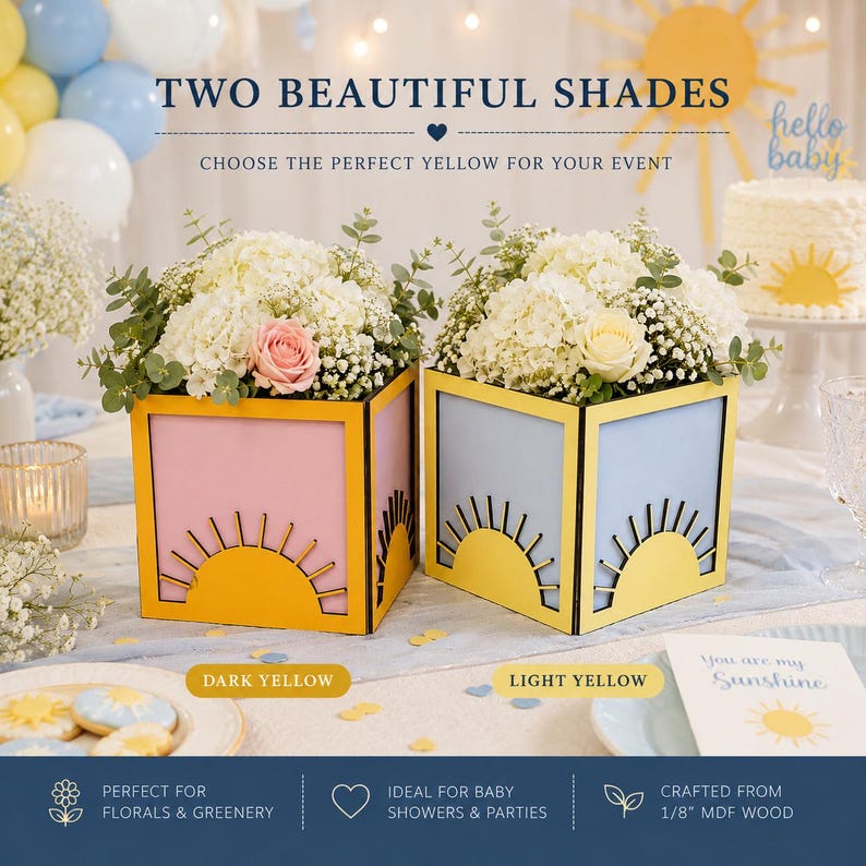 May include: Two square wooden boxes featuring a cutout sun design on the front. One box has a pink panel with a dark yellow sun, and the other has a light blue panel with a light yellow sun. Both are filled with white hydrangea and baby's breath.