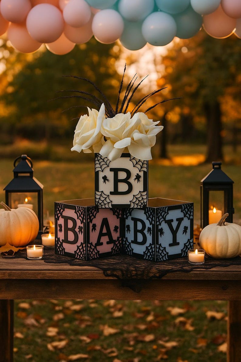Pode incluir: Uma decora&ccedil;&atilde;o para ch&aacute; de beb&eacute; com blocos de madeira que soletram "BABY". Os blocos s&atilde;o decorados com teias de aranha e as letras s&atilde;o rosa e azul. Rosas brancas e ab&oacute;boras tamb&eacute;m est&atilde;o presentes.