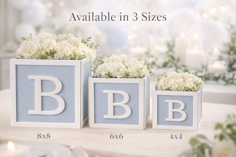 May include: Three square light blue and white decorative boxes, each featuring a large white letter B on the front. The boxes are filled with white flowers and labelled with sizes 8x8, 6x6, and 4x4 inches, with text Available in 3 Sizes.
