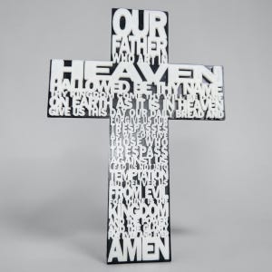 Pode incluir: Uma cruz preta com letras brancas em relevo que exibe o texto completo da oração do Pai Nosso, começando com Our Father Who Art In Heaven e terminando com Amen. O design utiliza um estilo de fonte sem serifa para todas as palavras.