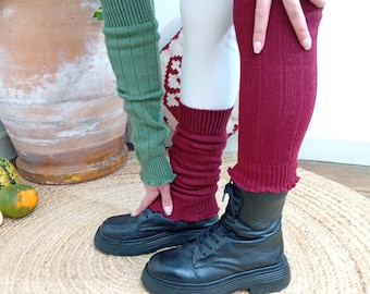 Könnte beinhalten: Ein Paar gerippte Strickstulpen in Olivgrün und Dunkelburgunder, getragen über weißen Leggings und kombiniert mit schwarzen Schnürstiefeln aus Leder. Die Stulpen haben ein strukturiertes vertikales Rippenmuster mit elastischen Bündchen.