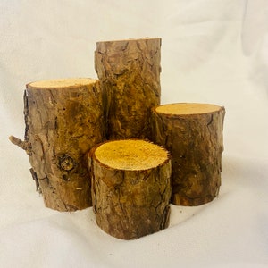 May include: Four wooden log slices stacked on top of each other, creating a tiered display. The logs are all different sizes and have a natural bark texture.