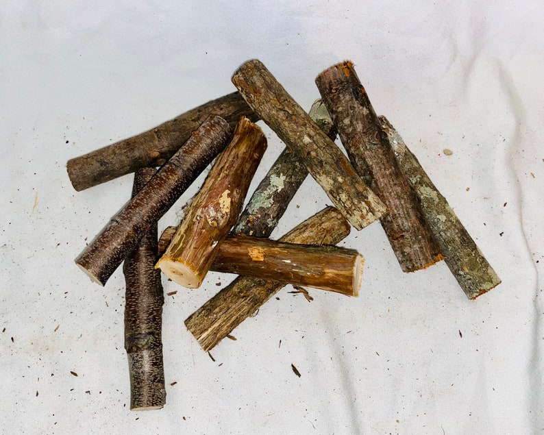 May include: A pile of small, brown and grey sticks of wood. The sticks are arranged in a random pattern on a white surface.