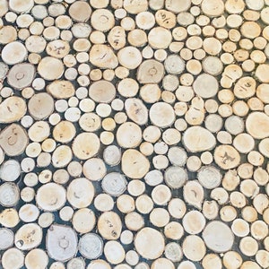 May include: A close-up of a wall made of many small, round, wooden pieces. The wood is a light brown color and the pieces are arranged in a random pattern.