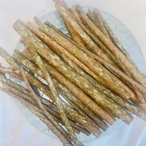 May include: A pile of brown sticks, likely for crafts or decor, arranged in a circular pattern on a silver tray.