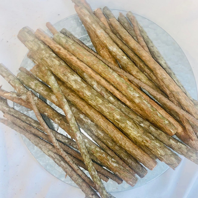May include: A pile of brown sticks, likely for crafts or decor, arranged in a circular pattern on a silver tray.