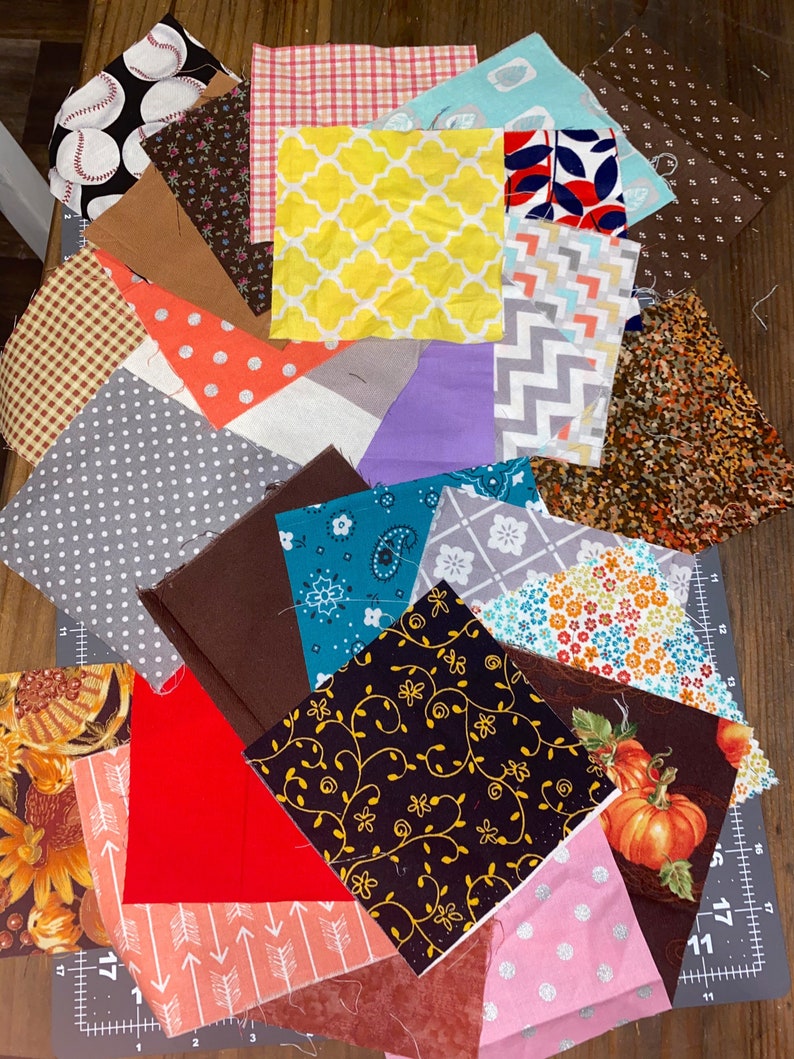 Puede incluir: Una colecci&oacute;n de cuadrados de tela en varios patrones y colores, incluyendo b&eacute;isbol, lunares, dise&ntilde;os florales y geom&eacute;tricos. Las telas est&aacute;n dispuestas sobre una esterilla de corte, mostrando una variedad de texturas e impresiones adecuadas para proyectos de acolchado o manualidades.