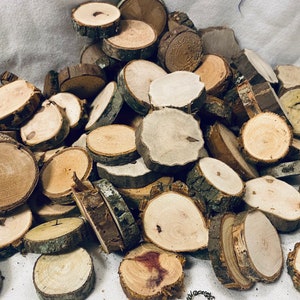 May include: A pile of natural wood slices, varying in size and color, with bark still attached to some. The wood slices are perfect for crafting projects, home decor, or wedding centerpieces.