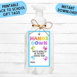 May include: A white soap dispenser with a gift tag that reads "HANDS DOWN THIS IS GOING TO BE THE BEST SCHOOL YEAR!" in colorful letters. The tag has handprints and the words "PRINTABLE BACK TO SCHOOL GIFT TAGS" and "INSTANT DOWNLOAD!" on it.