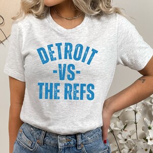 May include: A gray t-shirt with a blue graphic that says "DETROIT -VS- THE REFS".